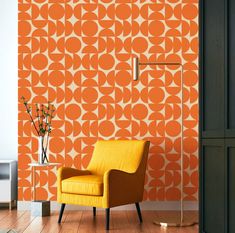 an orange chair sitting in front of a wall with circles on it and a lamp next to it