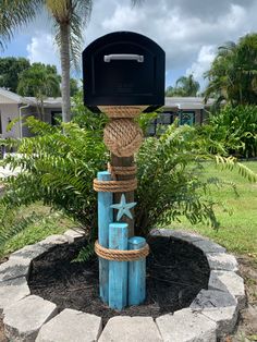 a mailbox with rope wrapped around it in the middle of a circle surrounded by palm trees