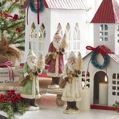 three santa figurines are standing in front of a christmas tree