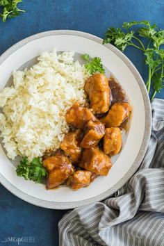 a white plate topped with rice and meat covered in sauce next to cilantro