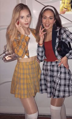 two young women standing next to each other in front of a white wall wearing plaid outfits