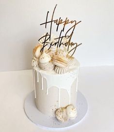 a birthday cake with white icing and seashells on the top that says happy birthday