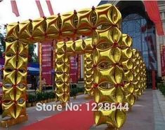 an archway made out of gold foil with red ribbon around it and eyes on the side