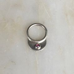 a silver ring with a pink stone in the middle on a white marble countertop