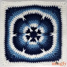 a blue and white crocheted square with an intricate design on the center is shown