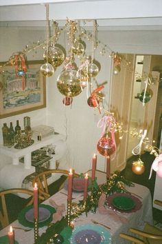 a dining room table set for christmas dinner with ornaments hanging from the chandelier