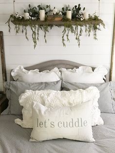 a bed topped with pillows and blankets next to a wall mounted shelf filled with candles