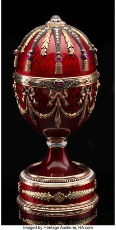 an ornately decorated red and gold egg on display in front of a black background