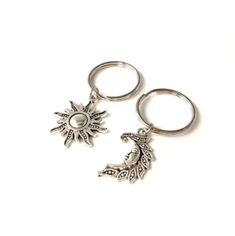 two metal key chains with charms attached to each other on a white surface, one has a sun and the other is a leaf