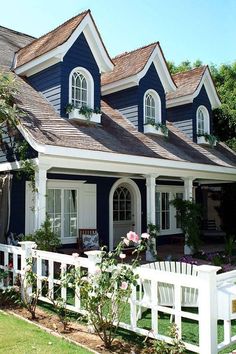 a blue house with white picket fence and flowers