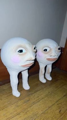 two white plastic animals standing next to each other on a wooden floor