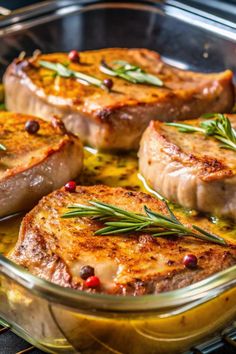 three pork chops in a glass dish with herbs and spices on the side, sitting on an oven rack