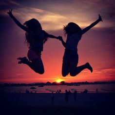 two girls jumping in the air at sunset