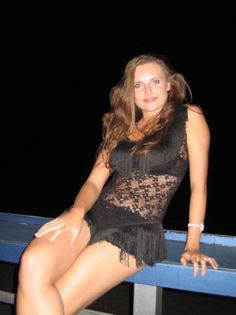 a woman sitting on top of a blue bench in a black lace dress and high heels