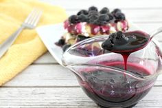 blueberry cheesecake in a glass bowl with sauce drizzled on top