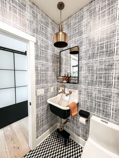 a bathroom with black and white wallpaper, a mirror, sink and toilet in it