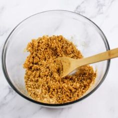 a wooden spoon in a glass bowl filled with crumbs