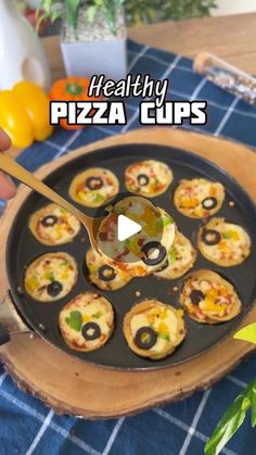 a person is holding a spoon over some mini pizzas on a pan with the words healthy pizza cups in front of them