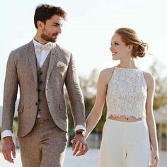 a young man and woman dressed in formal wear holding hands while walking down the street