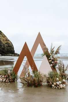 an artistic display on the beach with flowers and plants in it's centerpieces