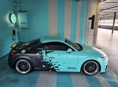 a blue and black car parked in a parking garage with graffiti on the side of it