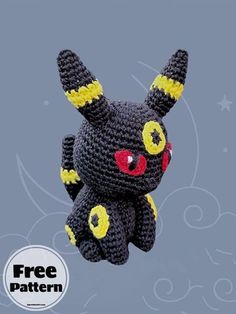 a crocheted black and yellow stuffed animal with red eyes flying through the air