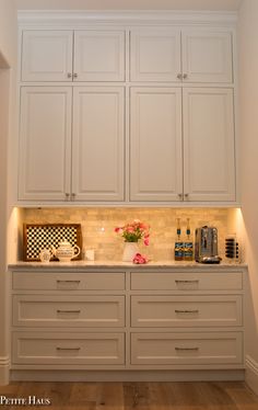 a kitchen with all white cabinets and counter tops in the corner, along with a coffee maker