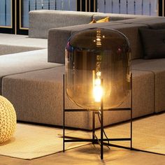 a lamp sitting on top of a metal stand in front of a couch and ottoman