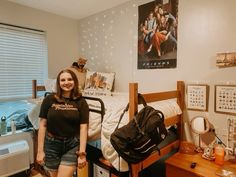 a woman standing next to a bed in a room with posters on the wall and other decorations