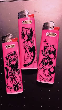 three pink lighters with black designs on them