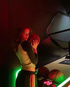 a woman holding a basketball in front of a neon sign with the word love on it