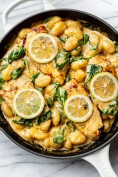 a skillet filled with chicken and lemons on top of a marble countertop