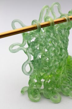 a close up of a knitting needle with green beads