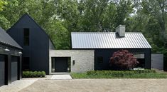 two black garages are next to each other in front of some trees and bushes