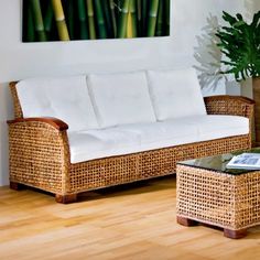 a wicker couch and coffee table in a living room with wood flooring, white cushions