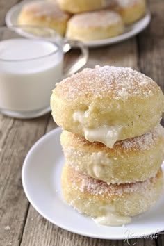 three sugary donuts stacked on top of each other next to a glass of milk