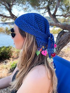 a woman wearing sunglasses and a blue hat with flowers on it's head sitting in a chair