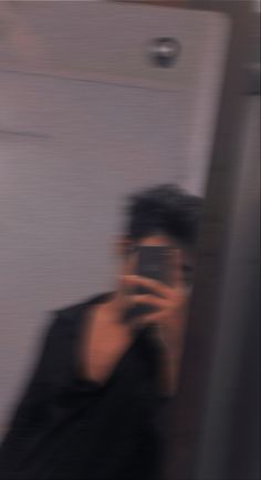 a blurry photo of a man holding a cell phone to his ear and taking a selfie