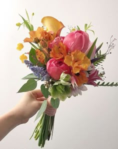 a bouquet of flowers being held by a person's hand on a white background