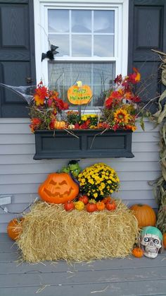 a porch decorated for halloween with hay and pumpkins