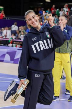 a woman is holding up her medal and smiling at the camera while standing in front of an audience