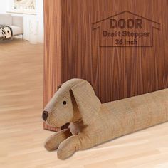 a stuffed dog sitting on top of a wooden floor in front of a sign that says door draft shopper