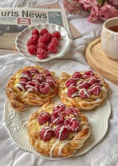 raspberry pastries with icing on a plate next to a cup of coffee