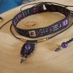 two bracelets are sitting on top of a piece of wood with beads and charms