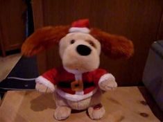 a stuffed dog dressed as santa clause sitting on a table