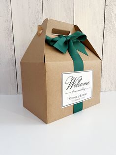 a brown box with a green ribbon and welcome sign on the front is sitting on a white surface