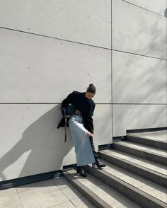 a person leaning against a wall with their back to the camera