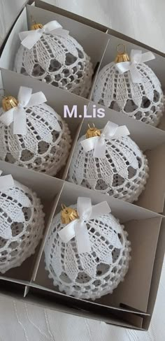 four white doily ornaments with bows in a box