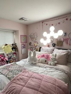 a bedroom with pink walls, white bedding and two stuffed animals on the bed