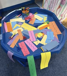 a blue table topped with lots of cut out pieces of paper and scissors on top of it